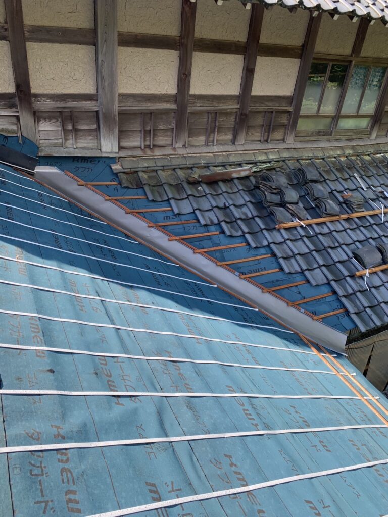 防水シートのゴムアルファルトルーフィング屋根ふき材を施工しました
白いテープは「きずり」と呼ばれ、その上に瓦桟を打ち付けていきます。きずりの厚み分、防水シートとの間に隙間が出来ます。それによって瓦の下に入った雨水が溜まらず軒下まで流れていきます。
