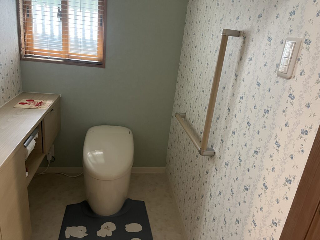 手摺、段差解消で安全に、優しいクロス柄で広々としたトイレ空間です。